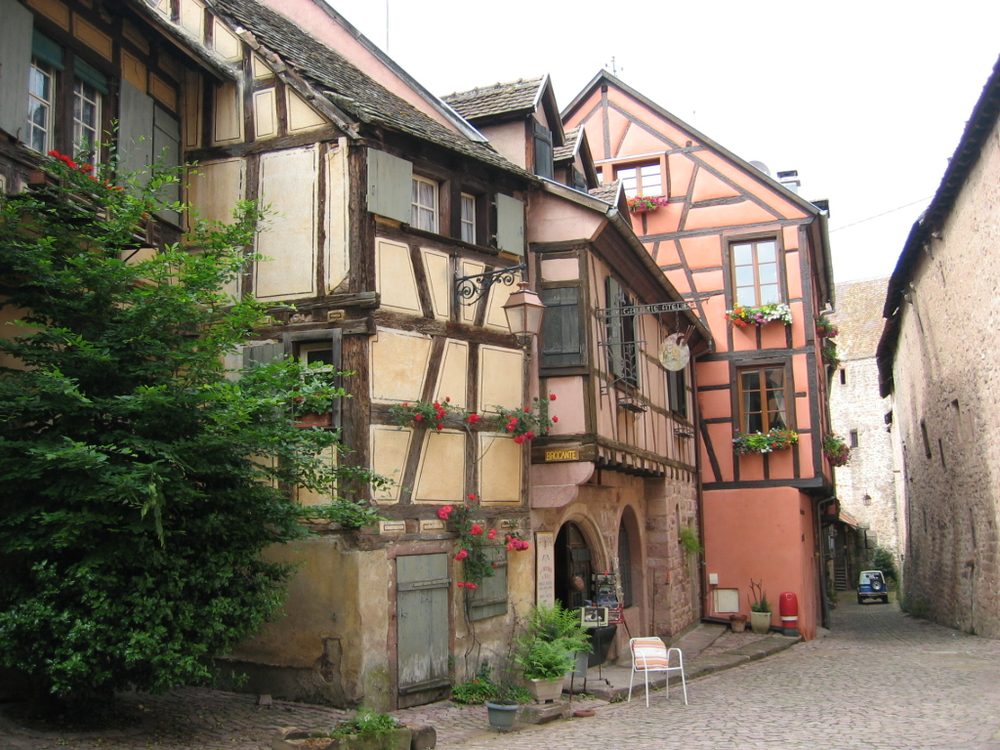 Une maison à colombages fleurie dans une rue de Riquewihr