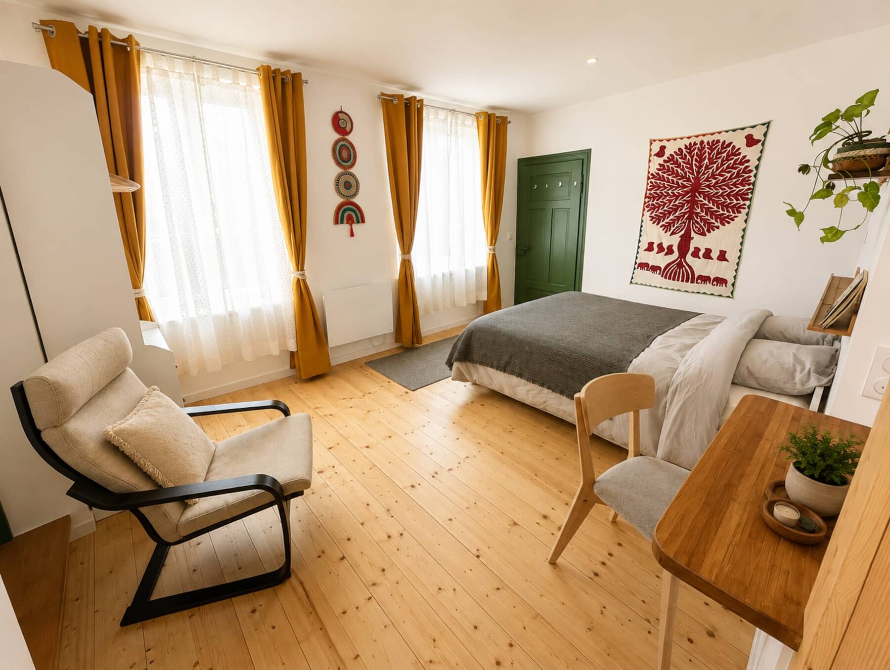 La chambre : lit queen size sous les poutres, rideaux moutarde et tenture indienne « arbre de vie » rouge