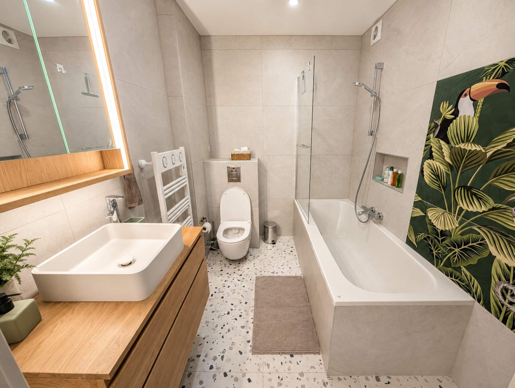 La salle de bain : baignoire, sol en terrazzo et fresque tropicale au toucan